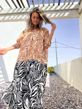 Vestido camisero largo con estampado de hojas en tonos marrones y blancos en la parte superior, y estampado de cebra en blanco y negro en la parte inferior.