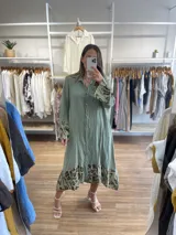 Vestido camisero largo de lino color beige con botones frontales, cuello camisero y mangas largas con puños. Presenta estampado animal print en mangas y ruedo.