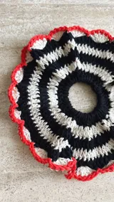 Gomita de pelo tejida al crochet con hilo de algodón a rayas en tonos rosa y violeta, con borde gris.