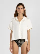 Camisa manga corta color marrón confeccionada en una mezcla de lino y tencel, con cuello camisero y cierre abotonado al frente.