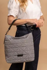 Bolso tipo shopper color beige con diseño acolchado geométrico y correa de hombro negra.