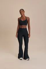 Calza negra de corte acampanado con aberturas laterales y bolsillo interno en la cintura.