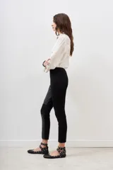 Pantalón negro de corte recto, con paneles de cuero sintético en los laterales y rodillas acolchadas.