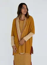 Saco azul de tejido de punto con rayas horizontales en tonos grises y detalles en rojo. Tiene corte holgado, mangas 3/4 y bolsillos laterales.