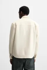 Sobrecamisa negra de tejido con elasticidad, cuello solapa y manga larga acabada en puño con botón a presión. Tiene bolsillos de plastrón en el pecho y cierre frontal con botones a presión.