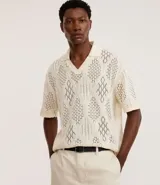 Camisa polo de mangas cortas color crema, confeccionada en tejido de punto calado con cuello inglés.