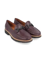 Mocasín de cuero negro con detalle de hebilla metálica plateada.