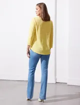 Blusa blanca de tejido labrado con cuello redondo, escote en V y aplique metálico.