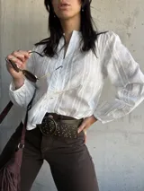 Camisa blanca con bordado floral, cuello mao y mangas largas abullonadas.