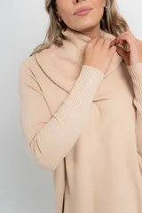 Sweater de punto color beige, con cuello amplio volcado y mangas largas acanaladas.