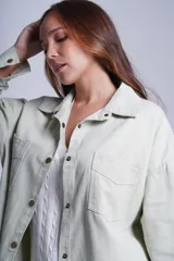 Sobrecamisa color beige de gabardina con cuello camisero, cierre frontal con botones a presión, dos bolsillos de parche en el pecho y corte holgado.