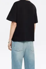 Camiseta blanca de corte boxy con escote redondo, manga corta recta y logo bordado con diseño floral.