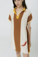 Vestido corto tejido en jersey liviano de algodón y acrílico, con diseño tipo polo y fit holgado. Presenta rayas verticales en color marrón y crudo, bordado XL de un ají y terminaciones en color amarillo.