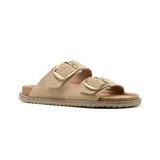 Sandalias bajas de cuero color beige con doble tira y hebillas metálicas doradas.