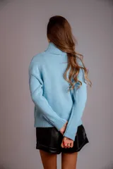 Sweater verde esmeralda de punto trenzado, con cuello alto y mangas largas.