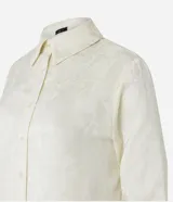 Camisa color crema en crepé con cuello solapa, abotonado frontal, mangas largas y textura de flores tramadas en el tejido.