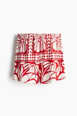 Short de tela color blanco con estampado de flores rojas, cintura elástica con cordón ajustable y bolsillos laterales.