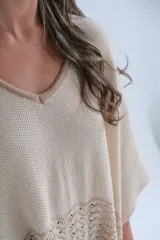 Poncho de tejido de punto color beige con guarda calada en el ruedo.