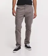 Pantalón de vestir marrón, de corte skinny, con bolsillos laterales y traseros. Se ajusta a la cintura con cinturón de cuero marrón.