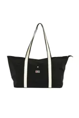 Bolso negro tipo tote con asas de hombro de cinta blanca. Tiene un bolsillo externo con botón a presión y cierre superior con cremallera.
