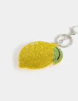 Llavero con dije de limón amarillo cubierto de strass y hoja verde. Incluye mosquetón metálico plateado para colgar en carteras, mochilas o bolsos.