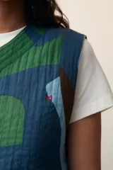 Chaleco acolchado con estampado abstracto en tonos azules y verdes, con cuello en V y cierre frontal con botones.