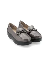Mocasín de cuero charol negro con plataforma blanca y detalle de hebilla metálica plateada en el empeine.