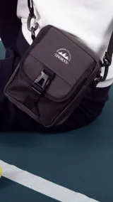 Morral verde militar con cierre, bolsillo delantero con presilla y broche de plástico, bolsillos internos y correa larga regulable.