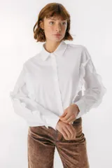 Camisa celeste con cuello clásico, cierre frontal con botones y mangas largas con volados.