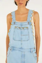 Enterito largo de jean celeste con tirantes ajustables con hebillas metálicas, bolsillo frontal y corte amplio.