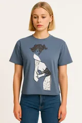 Remera celeste de algodón con estampado de una figura femenina en blanco y negro.