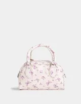 Cartera bowling de cuerina color blanco con estampado de mariposas lilas, doble asa corta y correa larga regulable y desmontable.