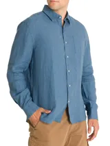 Camisa de manga larga azul con cuello clásico, cierre con botones y bolsillo en el pecho.