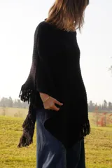 Poncho tejido en lana merino color crudo, con cuello alto y etiqueta de cuero con logo en la espalda.