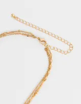 Collar corto dorado multicadena con dije de corazón y letra R.