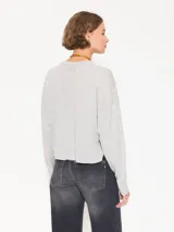 Sweater tejido suave y flojo, color crudo, con cuello redondo y mangas largas.