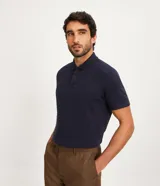 Polo azul marino de corte regular, confeccionada en algodón con textura de rayas horizontales. Tiene cuello inglés, botones en el pecho y mangas cortas.