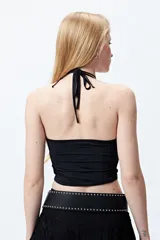 Top halter corto negro con tiras finas para anudar en la nuca.