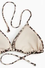 Top de bikini triangular con estampado de leopardo, tirantes finos y relleno extraíble. Se ata en la nuca y en la espalda.