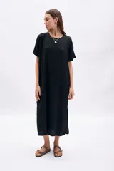 Vestido corto negro de manga corta y cuello redondo, con textura en la tela y corte recto y holgado.