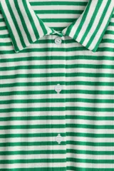 Camisa de manga corta en punto acanalado con rayas horizontales verdes y blancas, cuello clásico y botonadura frontal.