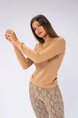 Sweater de cuello alto color beige, de tejido de punto fino.