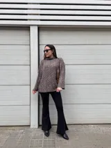 Sweater de punto con estampado animal print en tonos grises y marrones, cuello alto, corte holgado, más largo en la parte trasera y tajos laterales.