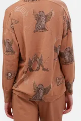 Cárdigan color marrón claro con estampado de aves, lunas y estrellas. Tiene escote en V, cierre con botones y bolsillos delanteros.