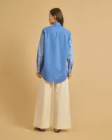 Camisa celeste holgada de manga larga con bolsillo en el pecho y cuello clásico.
