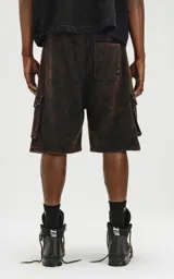 Bermuda cargo de algodón rústico, color marrón oscuro con efecto desgastado (acid wash/oxidado). Presenta un calce oversize, cintura elástica y grandes bolsillos laterales con tapa.