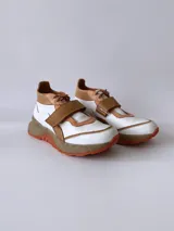 Zapatillas deportivas blancas con detalles en cuero color salmón y suela gruesa con detalles en naranja.