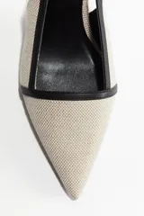 Zapato destalonado color beige con puntera fina y ribete negro. El taco es fino y mide 7 cm.