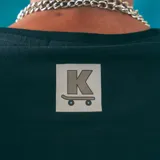 Remera negra de corte regular con estampa frontal de la marca KBA Industries con un diseño de una casa en llamas.