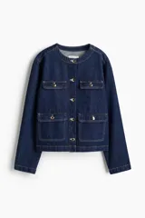 Campera de denim azul con cuello redondo, cierre frontal con botones dorados y cuatro bolsillos de parche con solapa y botón.